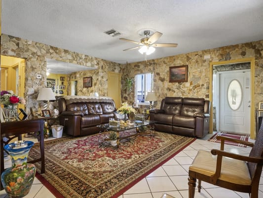 A comfortable living room with leather sofas and decorative stone walls.