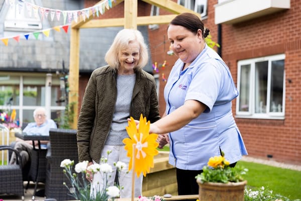 Staff member assisting a senior resident with gardening.