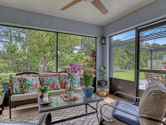 Comfortable sunroom with tropical decor and view of greenery