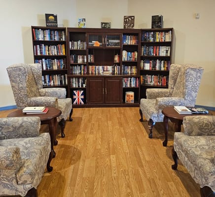 A cozy library area with armchairs and a bookshelf filled with books.