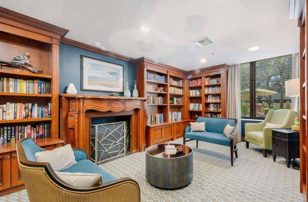 A comfortable library lounge with bookshelves, a fireplace, and seating areas.