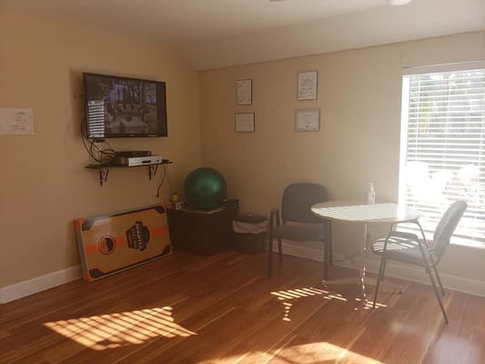 A cozy activity room featuring a television, chairs, and exercise ball.