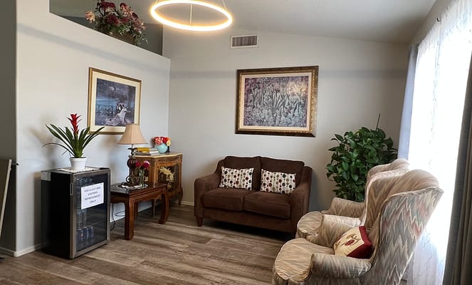 A cozy living room featuring a brown couch, patterned armchairs, and decorative plants.