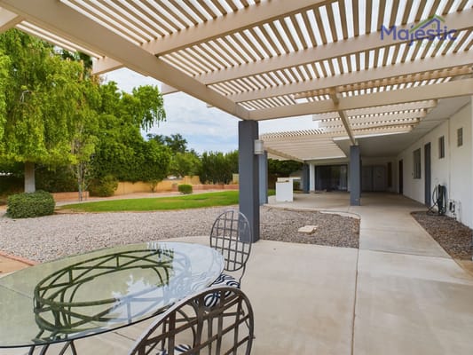 Outdoor patio area with glass table and chairs under a pergola