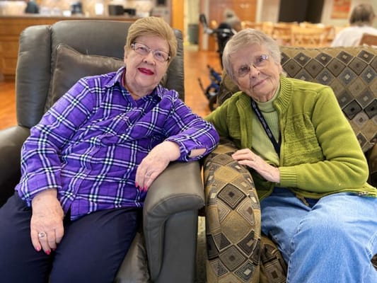 Two residents smiling together in a cozy lounge area