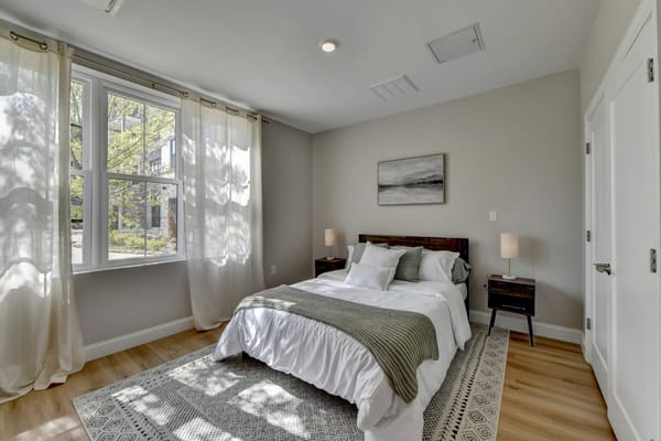 Brightly lit private resident room with a bed and artwork