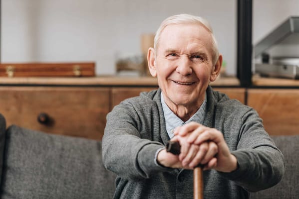 A smiling elderly man sitting in an interior space