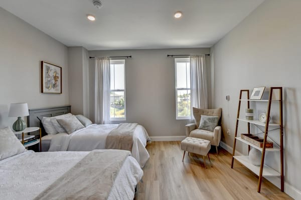 Well-lit resident room with two beds and seating area