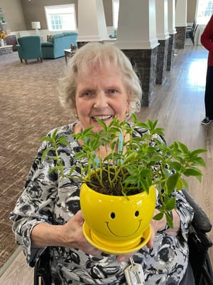 Resident smiling while holding a potted plant