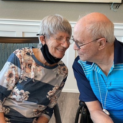 Two residents smiling at each other in a facility interior