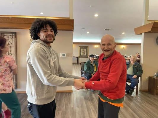 A staff member and resident dancing in a common area