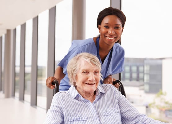 A nurse assisting a smiling resident in a hallway