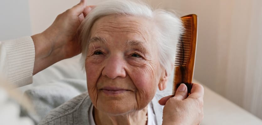 An elderly woman being groomed with a comb