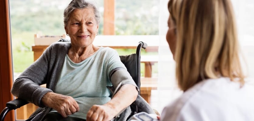 Resident smiling while receiving care from a staff member.
