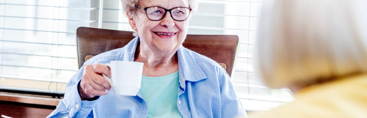 Senior resident smiling and holding a cup of coffee