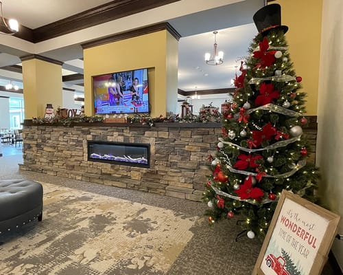 Festively decorated common area with a fireplace and television