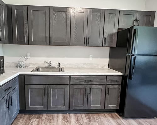 Modern kitchen area with dark cabinets and appliances