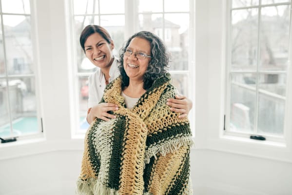 A caregiver and resident smiling together indoors