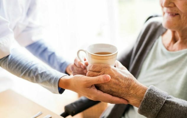 Caregiver assisting an elderly resident with a cup