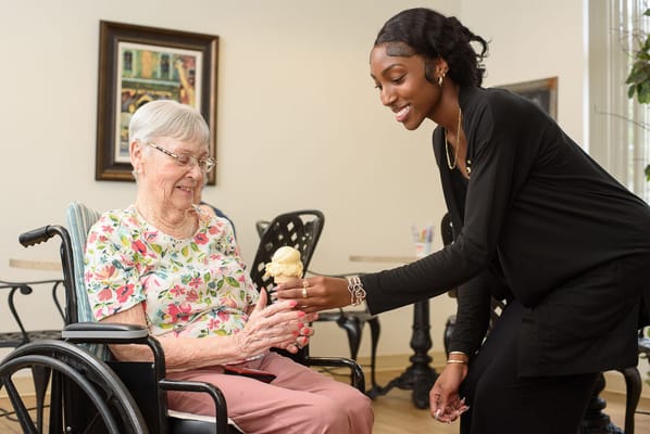 A caregiver serving ice cream to a resident in a bright room
