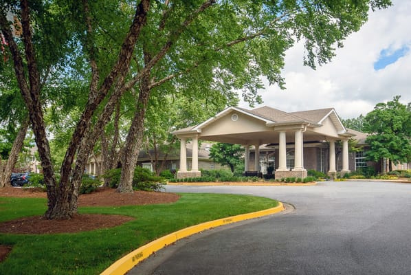 Entrance of a senior living facility surrounded by trees