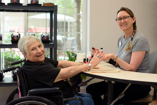 Resident receiving a manicure in a bright activity room