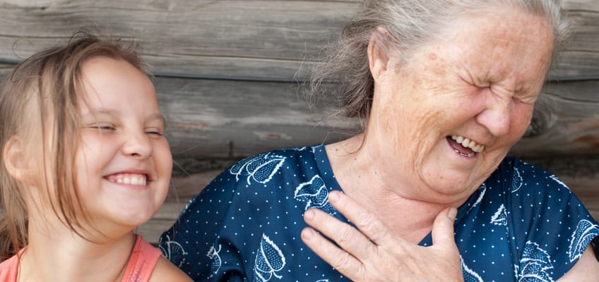 An elderly woman laughing with a young girl
