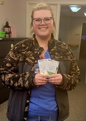 Staff member smiling and holding flyers in an interior space