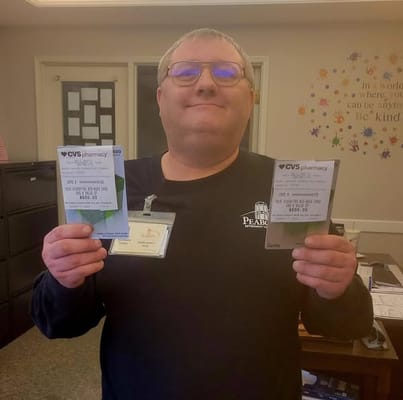 Staff member holding pharmacy cards at reception
