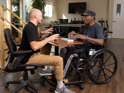 Therapist engaging in conversation with a resident in a wheelchair