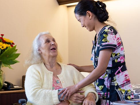 A staff member assisting a senior resident in a cozy room