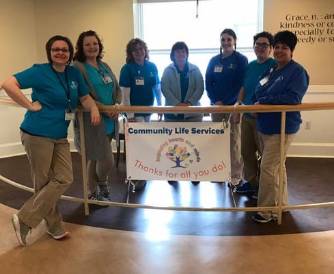 Staff members posing in a common area with a banner