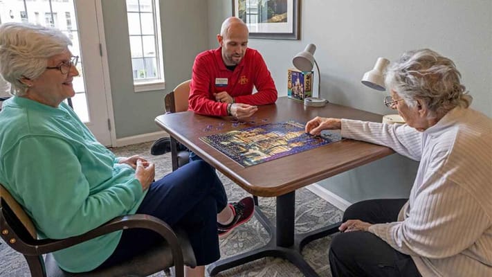 Residents and staff working on a puzzle together