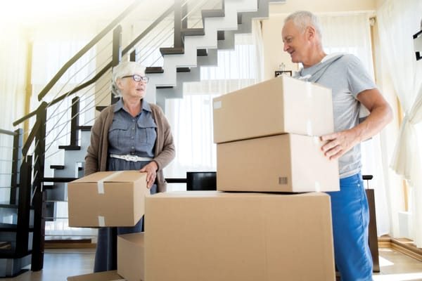 Two seniors unpacking boxes in a bright interior space