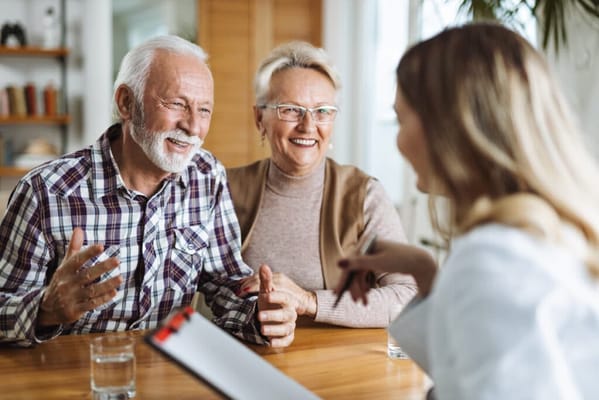 Two smiling seniors conversing with a staff member
