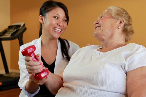 Staff assisting a resident with weights in a fitness activity