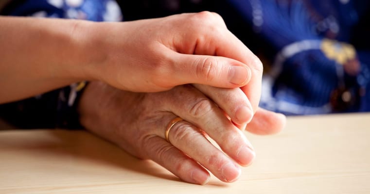 Two hands clasped together for comfort