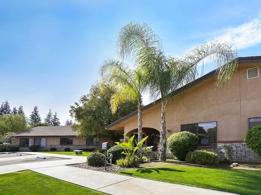 Exterior view of a senior care facility with palm trees