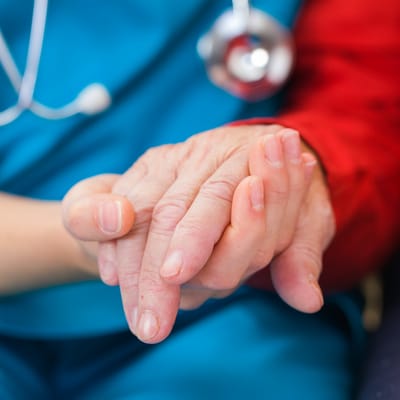 Healthcare provider gently holding a resident's hand