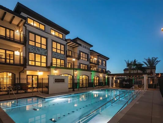 Exterior view of a building with a pool area at twilight