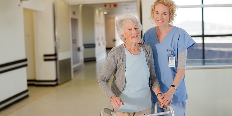 A staff member assisting a resident in a hallway