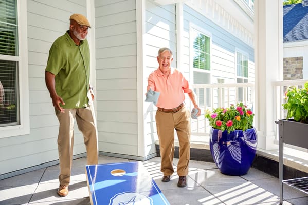 Two residents playing cornhole in an outdoor area