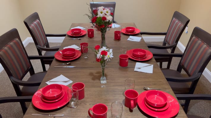 A dining table set with red plates and flowers