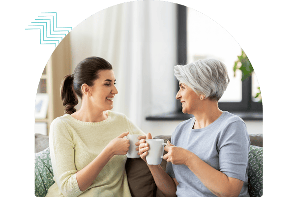Two residents chatting with coffee cups in a cozy setting