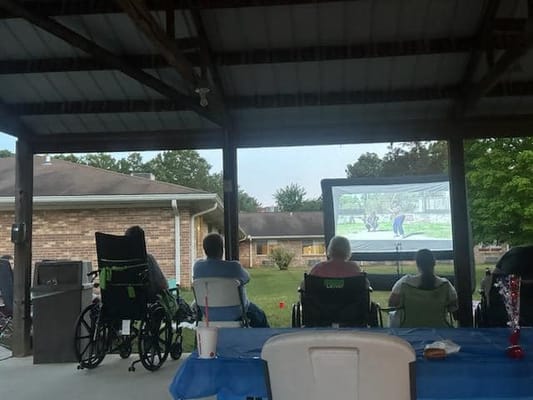 Residents watching a movie outdoors in wheelchairs