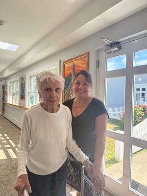 Resident and staff member smiling in a hallway