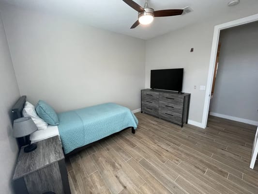 A simple and modern private resident room with a bed and TV