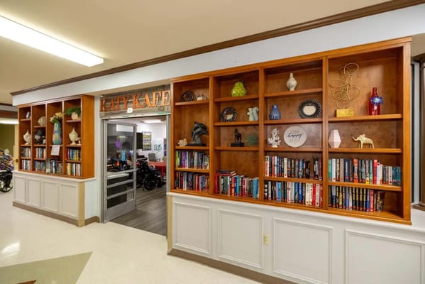 Interior of a cozy reading area with shelves and cafe entrance