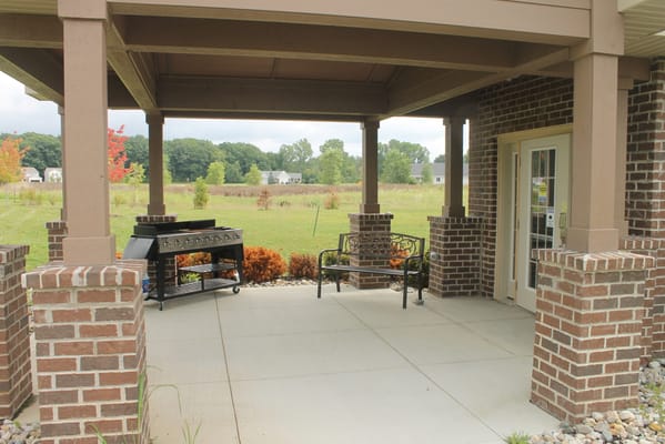 Patio area with grill and seating overlooking landscaped grounds