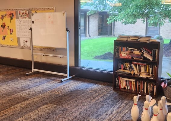 Common area with a bookshelf and view of green space